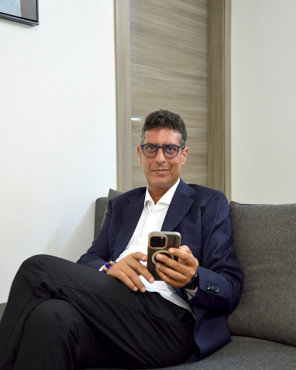 Gianluca Cricrì seduto mentre consulta il telefono